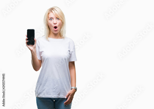 Young beautiful blonde woman showing screen of smartphone over isolated background scared in shock with a surprise face, afraid and excited with fear expression