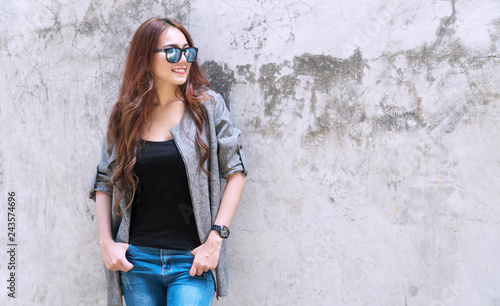 Professional business of young woman wearing sunglasses looking at something while standing on concrete walls background with copy space.