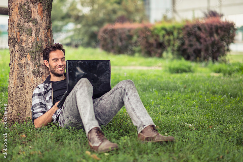 Modern freelance man enjoying his work in nature, typing on his laptop, finishing a project for a client Modern freelance man enjoying his work in nature, typing on his laptop, finishing a project for a client
