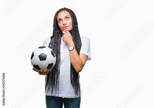 Young braided hair african american girl holding soccer ball over isolated background serious face thinking about question, very confused idea