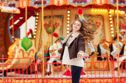 Beautiful happy woman with long vawy hair smiling over winter carousel .