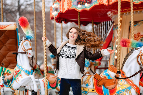 Beautiful happy woman with long vawy hair smiling over winter carousel . photo