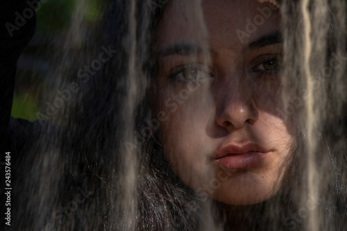 Retrato de mujer joven en plano cerrado derramando arena por delante de su cara © Trepalio