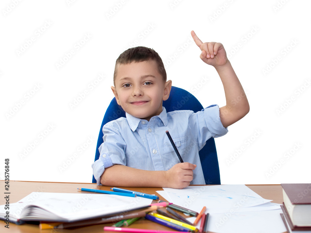 boy student sits drawing with colored pencils and shows index finger upwards boy student sits drawing with colored pencils and shows index finger upwards