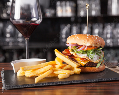 American food, Cheeseburger - Delicious gourmet burger with fries, served on a wooden table with a glass of red wine