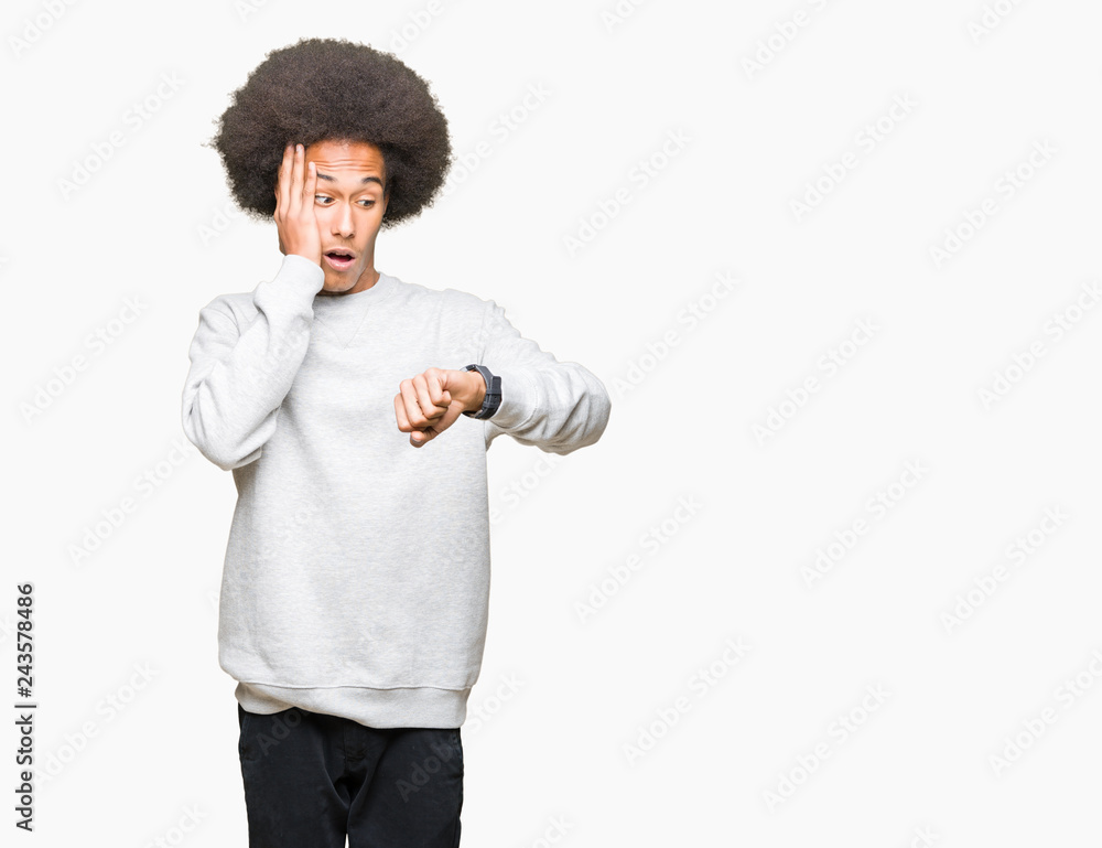 Young african american man with afro hair wearing sporty sweatshirt Looking at the watch time worried, afraid of getting late Young african american man with afro hair wearing sporty sweatshirt Looking at the watch time worried, afraid of getting late