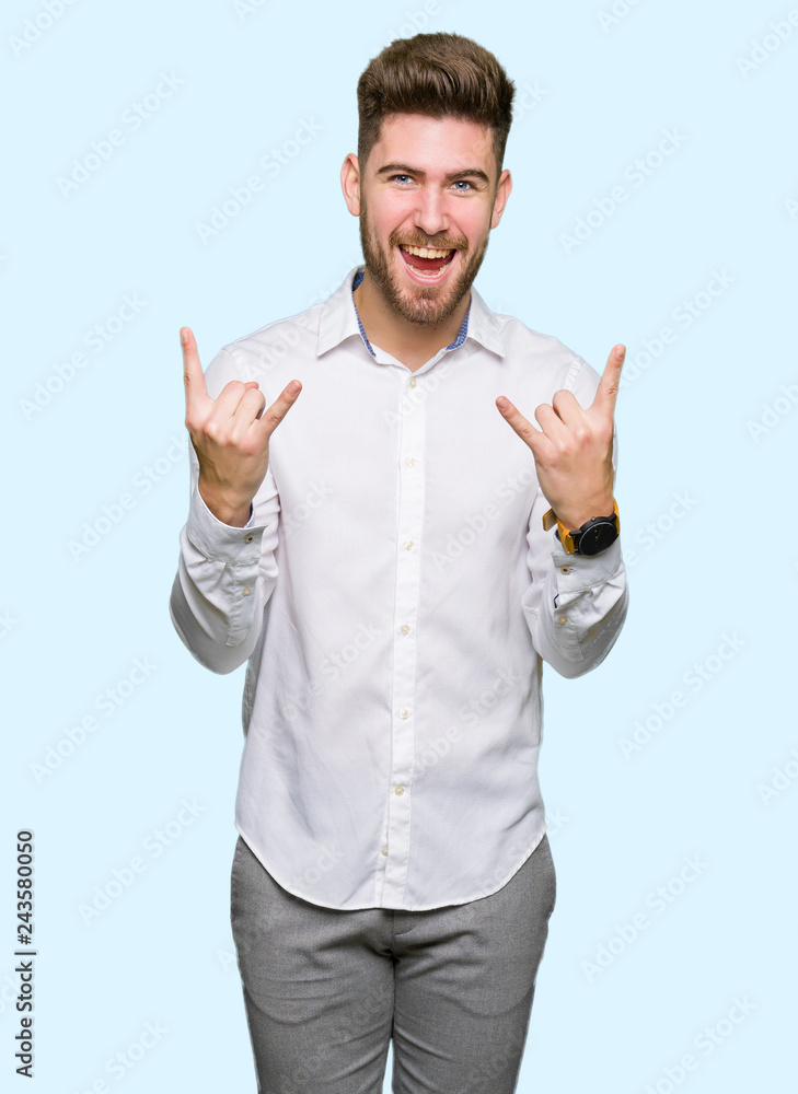 Naklejka premium Young handsome business man shouting with crazy expression doing rock symbol with hands up. Music star. Heavy concept.