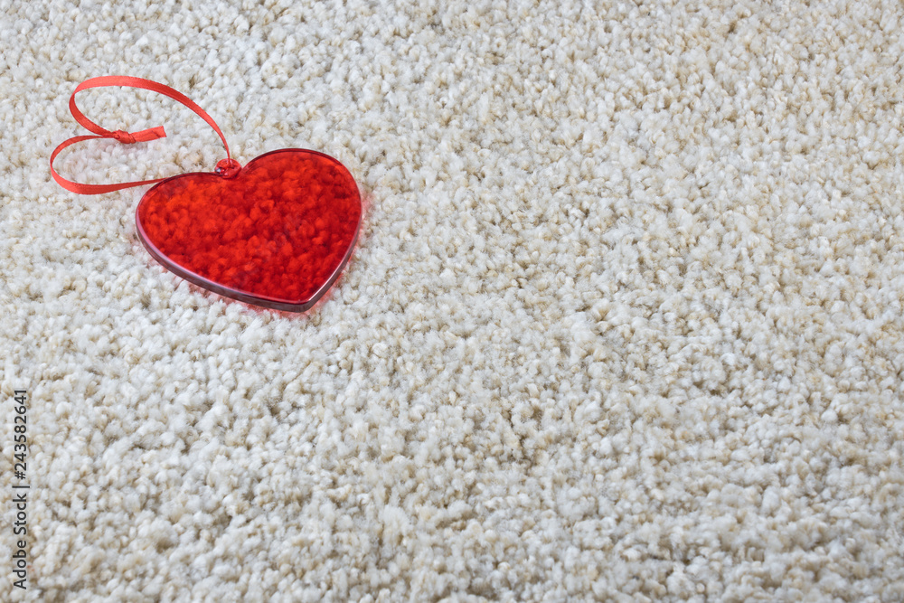 A red glass heart on a carpet love and Valentine concept. Copy space. A red glass heart on a carpet love and Valentine concept. Copy space.