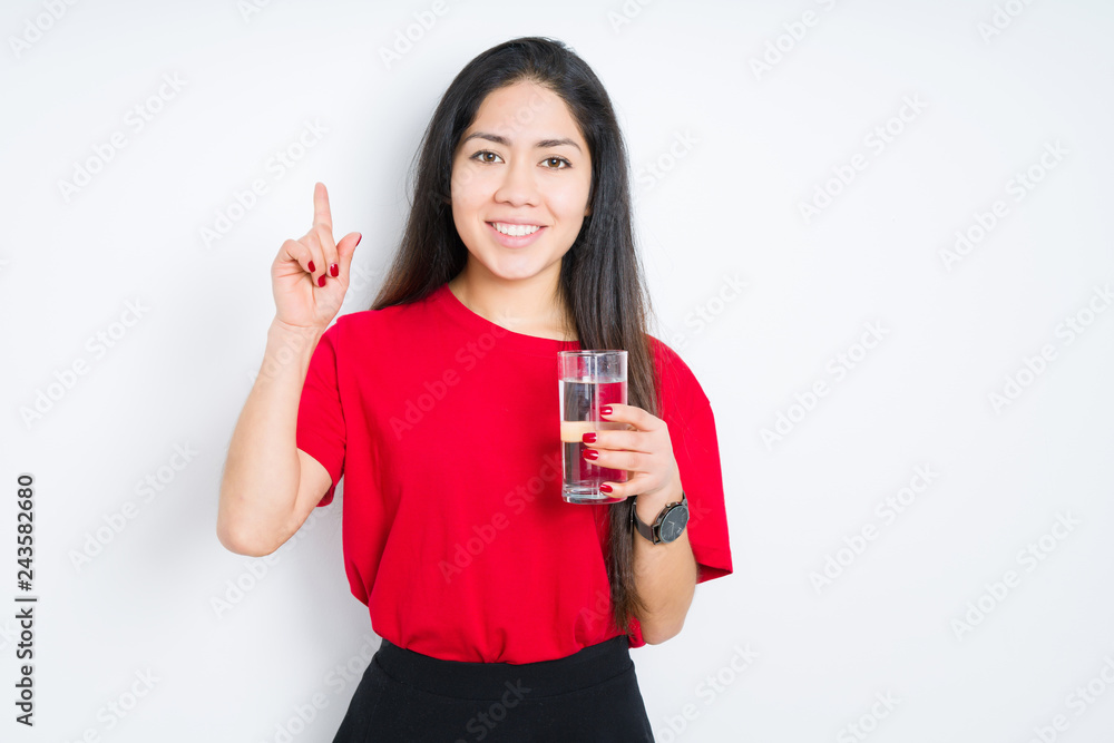 Young brunette woman drinking a glass of water over isolated background surprised with an idea or question pointing finger with happy face, number one Young brunette woman drinking a glass of water over isolated background surprised with an idea or question pointing finger with happy face, number one