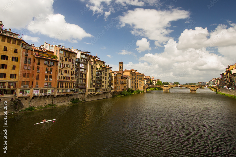 Morning Exercise - A lone oarsman rows along the Arno River on a beautiful summer morning. Ponte Vecchio over River Arno. Florence, Italy