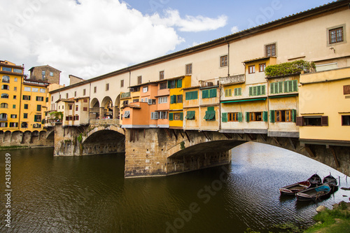 The Shopping Bridge with Boats Moored - Boats await their customers under colorful Ponte Vecchio - a bridge hosting many jewelry shops - that crosses the River Arno. Florence, Italy