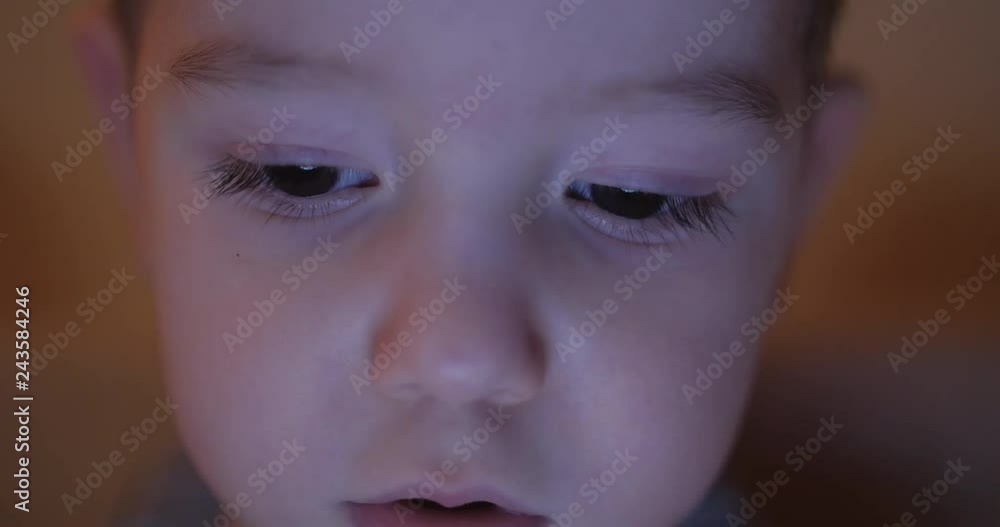 Night picture of a happy child's face looking at a tablet PC with light reflection in his eyes. Night picture of a happy child's face looking at a tablet PC with light reflection in his eyes.