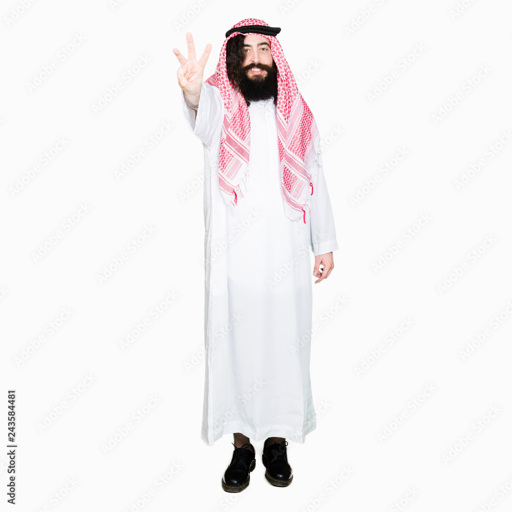 Arabian business man with long hair wearing traditional keffiyeh scarf showing and pointing up with fingers number three while smiling confident and happy. Arabian business man with long hair wearing traditional keffiyeh scarf showing and pointing up with fingers number three while smiling confident and happy.