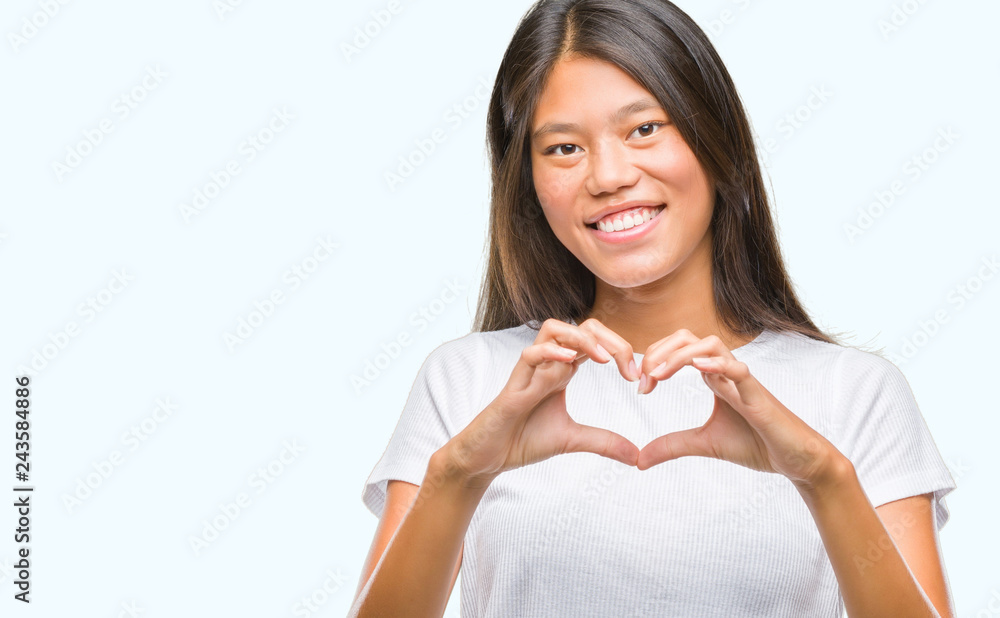 Young asian woman over isolated background smiling in love showing heart symbol and shape with hands. Romantic concept. Young asian woman over isolated background smiling in love showing heart symbol and shape with hands. Romantic concept.