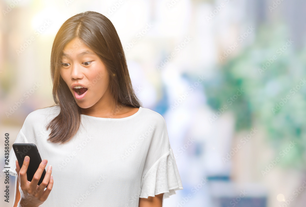 Young asian woman texting using smartphone over isolated background scared in shock with a surprise face, afraid and excited with fear expression