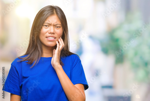 Young asian woman over isolated background touching mouth with hand with painful expression because of toothache or dental illness on teeth. Dentist concept.