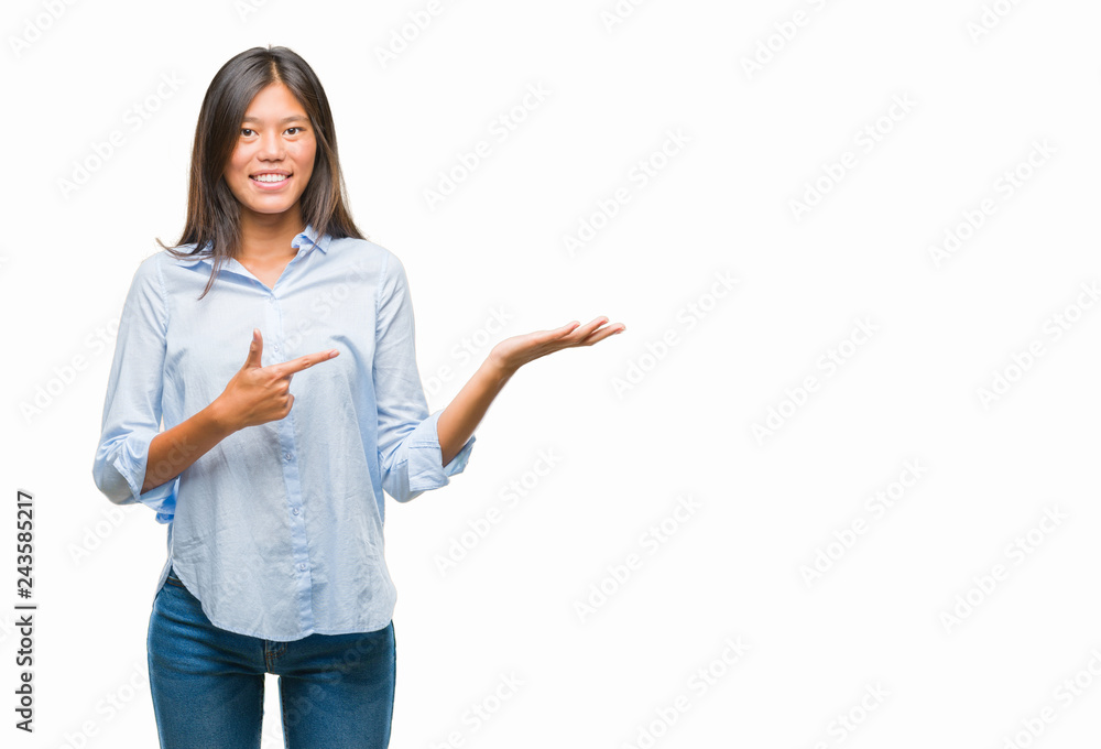 Young asian business woman over isolated background amazed and smiling to the camera while presenting with hand and pointing with finger. Young asian business woman over isolated background amazed and smiling to the camera while presenting with hand and pointing with finger.