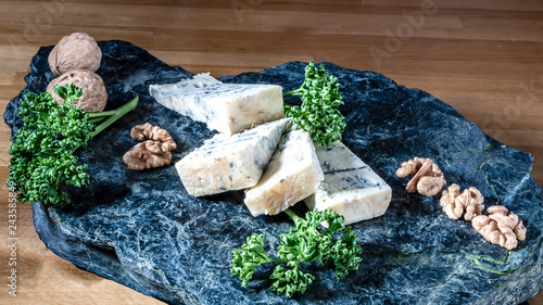 Cheese from France named Tommette des Alpes on the natural black stone platewith shadow photo