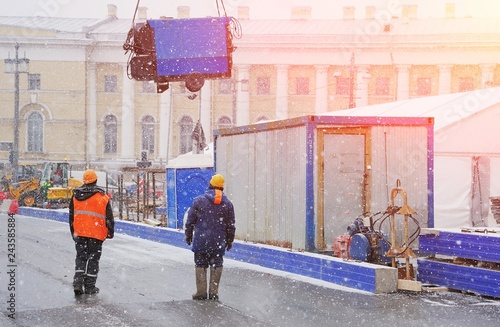 Unloading equipment for construction works in the city centre. Civil engineer at construction site is inspecting ongoing works in difficult winter conditions