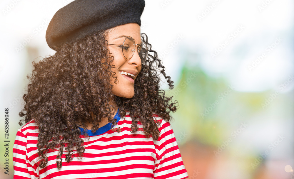 Young beautiful woman with curly hair wearing glasses and fashion beret  looking away to side with smile on face, natural expression. Laughing  confident. Stock Photo | Adobe Stock