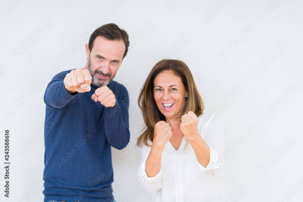 Beautiful middle age couple in love over isolated background Punching fist to fight, aggressive and angry attack, threat and violence Beautiful middle age couple in love over isolated background Punching fist to fight, aggressive and angry attack, threat and violence
