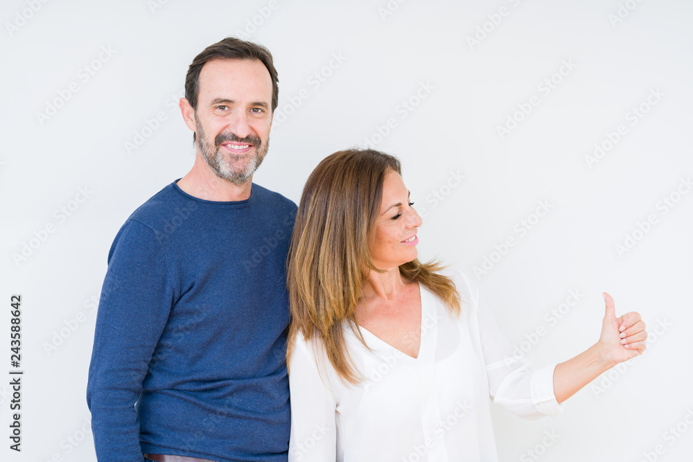 Beautiful middle age couple in love over isolated background Looking proud, smiling doing thumbs up gesture to the side Beautiful middle age couple in love over isolated background Looking proud, smiling doing thumbs up gesture to the side