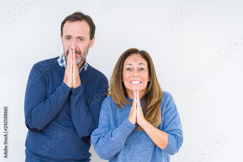 Beautiful middle age couple in love over isolated background praying with hands together asking for forgiveness smiling confident.