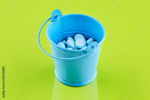 Blue metal bucket with pills on green background