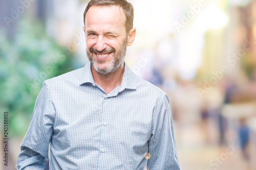 Middle age hoary senior business man over isolated background winking looking at the camera with sexy expression, cheerful and happy face.