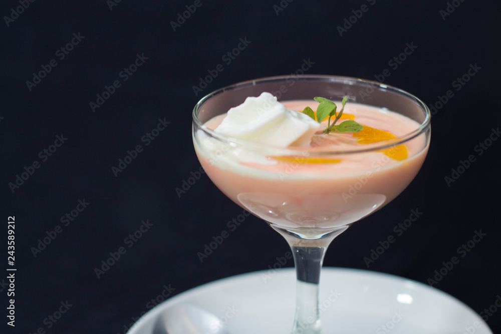Postre melocotón y crema batida en copa vidrio con fondo obscuro Postre melocotón y crema batida en copa vidrio con fondo obscuro