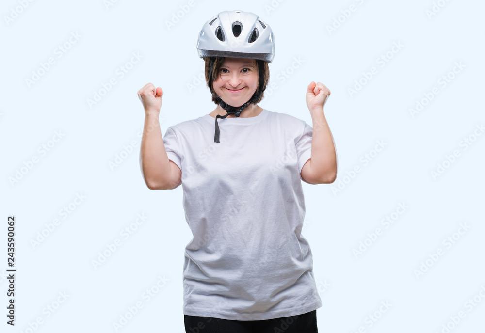 Young adult cyclist woman with down syndrome wearing safety helmet over isolated background celebrating surprised and amazed for success with arms raised and open eyes. Winner concept. Young adult cyclist woman with down syndrome wearing safety helmet over isolated background celebrating surprised and amazed for success with arms raised and open eyes. Winner concept.