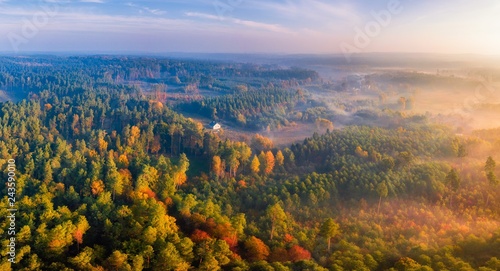 Aerial landscape with house and foggy sunrise over meadows and forest