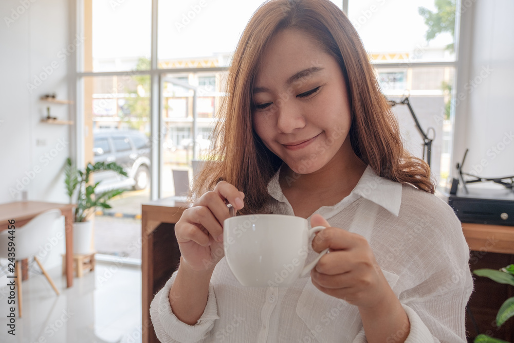A beautiful Asian woman holding and drinking hot coffee with feeling good in cafe A beautiful Asian woman holding and drinking hot coffee with feeling good in cafe