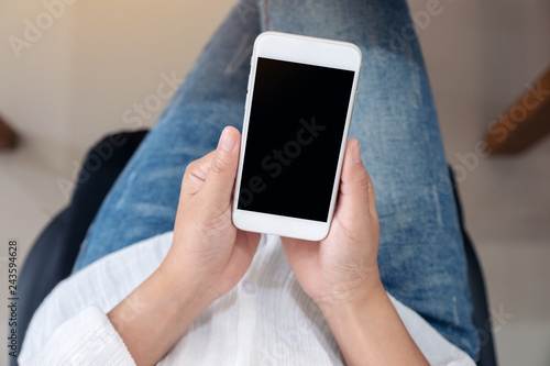 Top view mockup image of hands holding and using a white mobile phone with blank screen while sitting © Farknot Architect