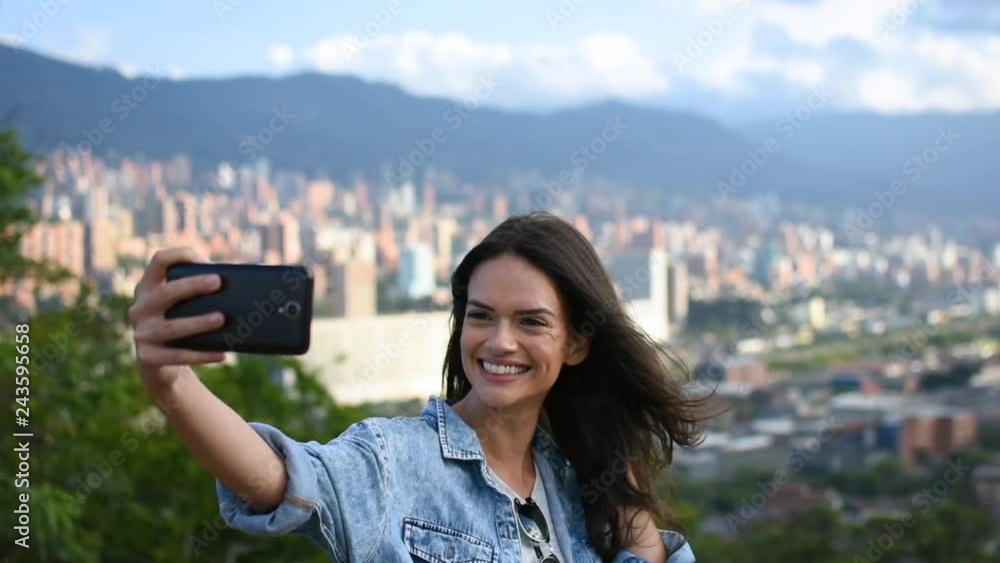 Beautiful happy model taking selfie in front of the cityscape panorama, Smiling Caucasian young pretty woman taking pics with her self phone, urban city background Beautiful happy model taking selfie in front of the cityscape panorama, Smiling Caucasian young pretty woman taking pics with her self phone, urban city background
