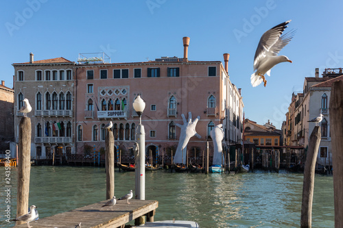 Giant hands rise from the water of Grand Canal to support the building in Venice.