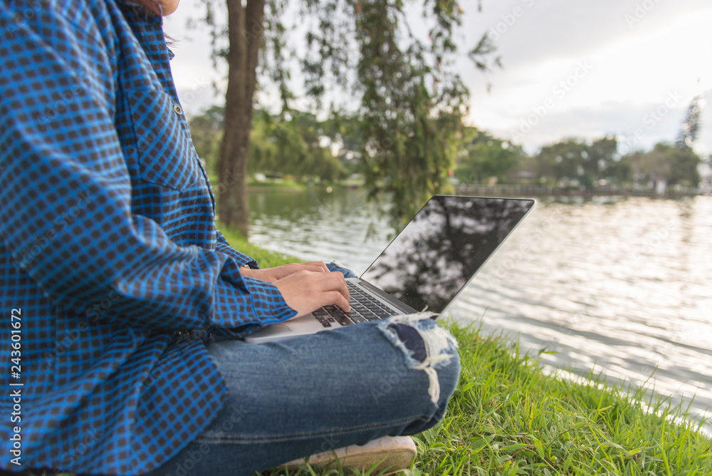 Young writer working with laptop next to a lake in the beautiful park Young writer working with laptop next to a lake in the beautiful park