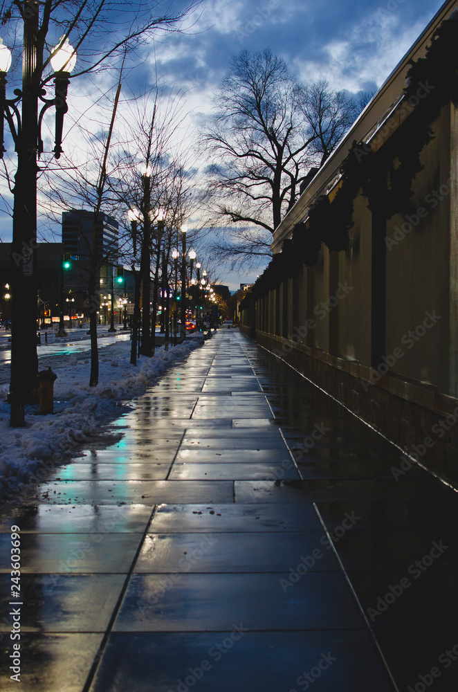 Obraz premium The wet sidewalk along the dim lit city street in salt lake. 