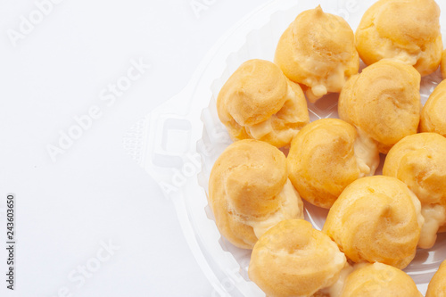 Profiteroles or Thai call Eclair in plastic box isolated on white background.