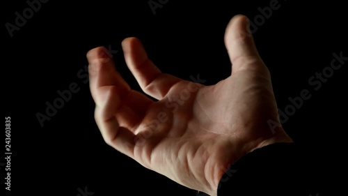 Human male palm in the rays of light isolated on black background. A man shows an open hand, then slowly clench his fingers into a fist and again unclenched. Stock video slow motion