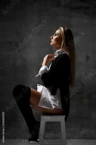 Young sexy sensual blonde fashion woman portrait posing in white man shirt and jacket on dark