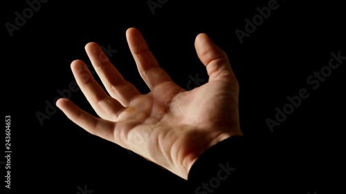 Male hand clenched in fist in rays of light isolated on black background. Fingers slowly open themselves and show empty palm, then clenched back into fist. Presentation concept, slow motion video.