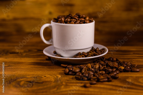 White cup filled with coffee beans on wooden table