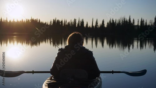 Woman sitting in a kayak, enjoying a sunset. It is very calm and serene. photo
