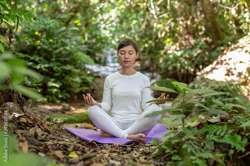 Beautiful girls are playing yoga at the park. Among the natural waterfalls in the forest, exercise concepts