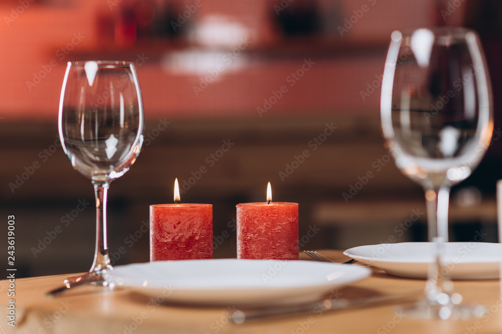 two glasses of wine and burning candles on a festively served table close-up
