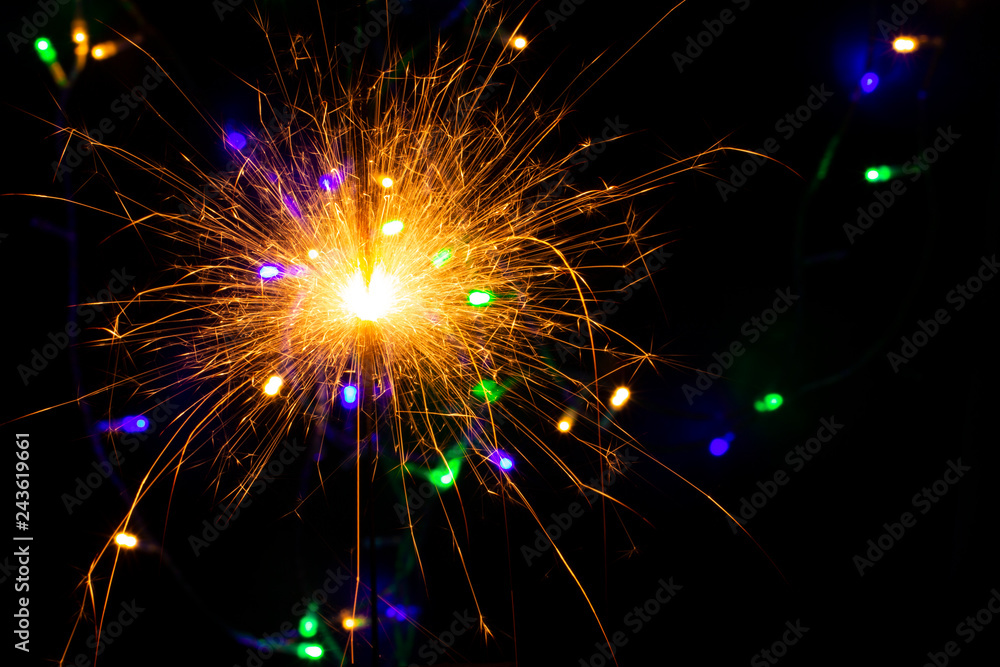 Naklejka premium festive background with sparkler and new year lights closeup