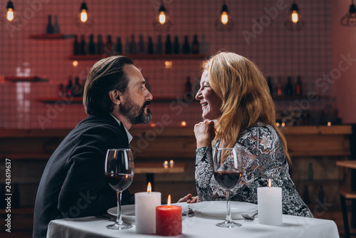 Man and woman are looking in love at each other while sitting at a table in a restaurant.