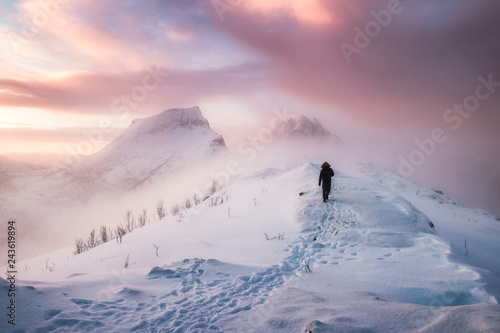 Vászonkép Man mountaineer walking with snow footprint on snow peak ridge in blizzard