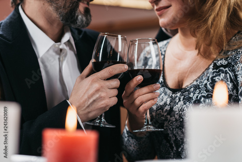 Man and woman raise glasses with red wine close up